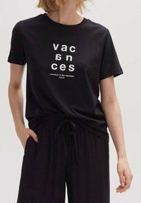 Svart bomullströja med vit text "vacances" och "summer is the warmest color", med en avslappnad passform och rundad halsringning.