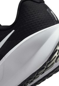 Zapatilla deportiva negra con parte superior de malla texturizada, entresuela blanca en contraste y suela de goma con un dibujo para un mejor agarre.