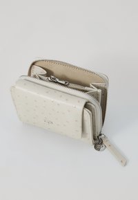 White leather wallet with textured surface, zippered closure, multiple compartments, and a small charm on the zipper pull.