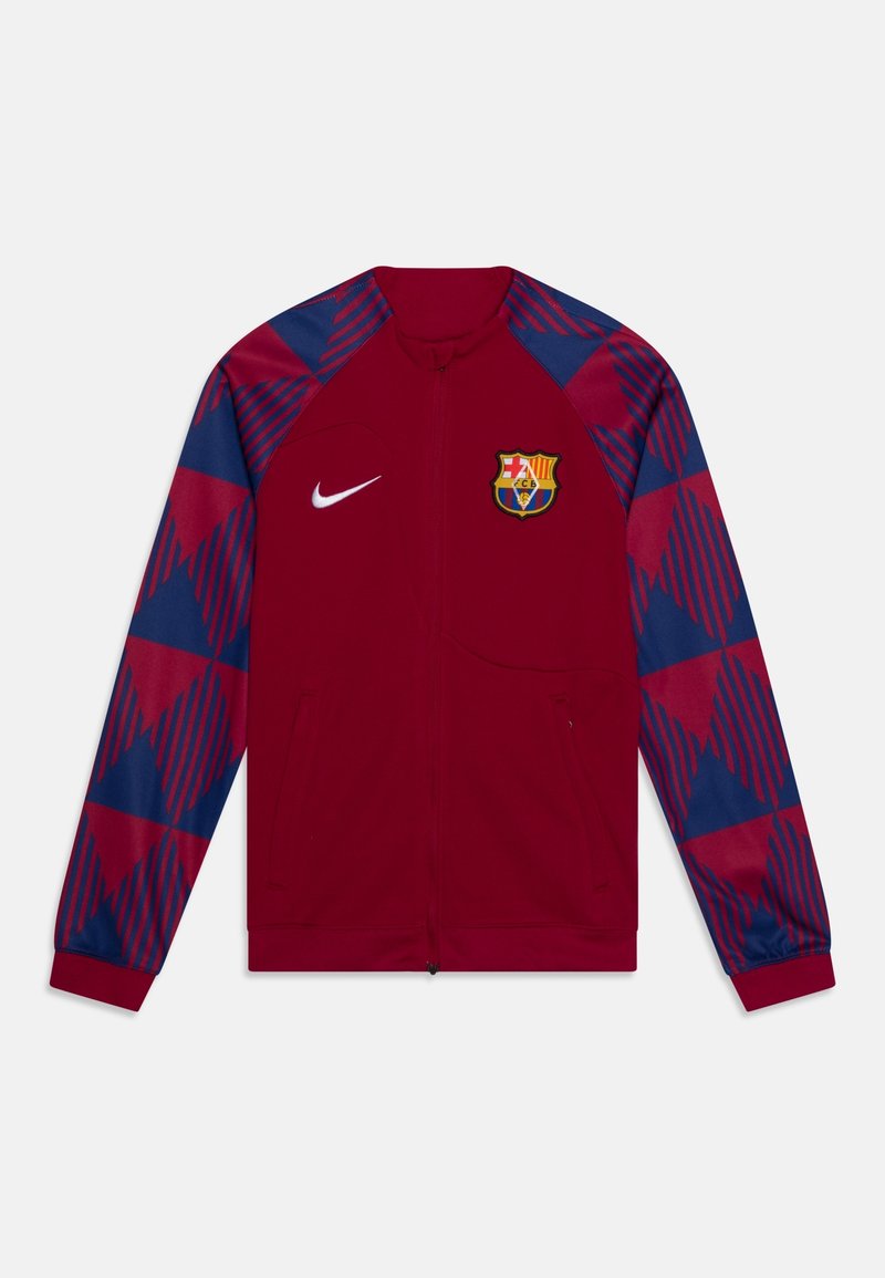 Nike track jakke i rød med blå geometriske mønstre på ærmerne, med en forreste lynlås og et broderet FC Barcelona-logo.