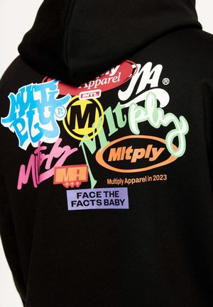 Sweat à capuche noir avec des logos texte colorés et superposés, dont « Multiply », « Mltply », « Multiply Apparel en 2023 » et « FACE THE FACTS BABY ».
