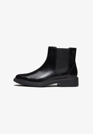 Bottine en cuir noir avec panneaux latéraux élastiques, talon bas et semelle texturée, montrée de profil sur fond blanc.