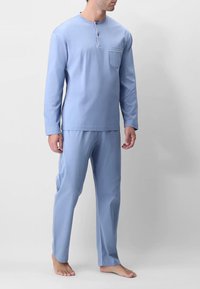 Set di pigiama in cotone azzurro chiaro composto da una maglia a maniche lunghe con scollo henley e taschino sul petto, abbinata a pantaloni dritti coordinati.