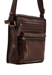 Brązowa skórzana torba crossbody z dwiema przednimi zamkami błyskawicznymi, regulowanym paskiem i detalami przeszyć. Posiada wytłoczone logo z boku.
