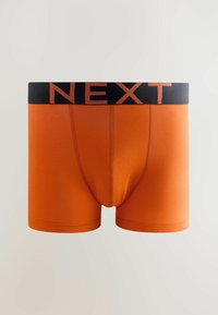 Boxeri portocalii dintr-un material moale, cu un talie neagră pe care se află cuvântul "NEXT" scris cu litere portocalii îndrăznețe.