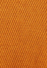 Gros plan sur un tissu tricoté orange présentant une texture côtelée verticale et un motif de points détaillé.