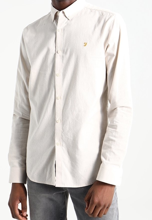 Hellbeige Hemd aus Baumwolle mit durchgehender Knopfleiste. Verfügt über einen strukturierten Kragen, lange Ärmel und ein dezentes gelbes Logo auf der Brust.