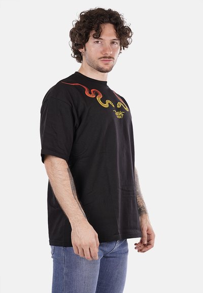 Maglietta in cotone nera con scollo rotondo, caratterizzata da un design di serpente rosso e giallo sul petto. Maniche corte e vestibilità rilassata.