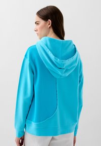 Turquoise hoodie met een zachte textuur, voorzien van een naaddetail langs de rug en geribbelde manchetten en onderrand.