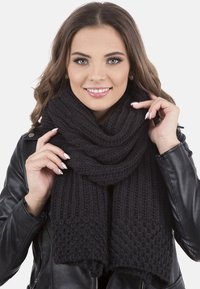 Black knitted scarf with a textured pattern, wrapped loosely around the neck, showcasing a soft, chunky knit design.