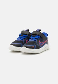 Chaussures de sport noires et bleues avec un matériau en maille, des accents rouges contrastants et une sangle velcro sur les lacets pour un ajustement sûr. Semelle blanche.
