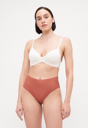 Bijela bežična bralette s dubokim izrezom, uparen s visokim gaćicama boje rđe, s glatkom teksturom i minimalističkim dizajnom.