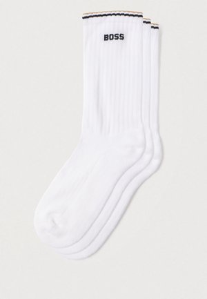 Bijele rebraste čarape s crnim logotipom "BOSS" i horizontalnim prugama u crnoj i narančastoj boji na rubu. Meka tekstura.