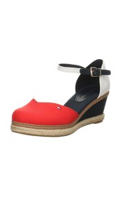 Sandalía cuña roja y blanca con tira de tobillo azul marino, suela estilo espadrille, punta redonda y costura decorativa. Presenta un pequeño detalle de logo.