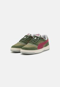 Green suede and textile sneakers with a pink textile accent, white midsole, and grey lining. Features laces and a logo tag on the tongue.