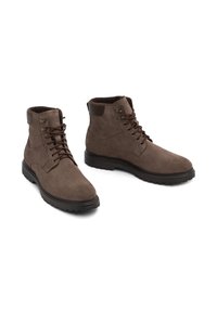 Pruunid seemisnahast pahkluu saapad, millel on sidumisfront, pehmendusega krae ja kummist välistald, millel on mustriga kulumine haardevõimekuse tagamiseks.