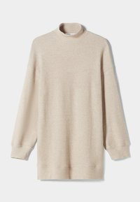 Beige ribbad tröja med hög polokrage, långa ärmar och en avslappnad passform. Har en mjuk textur och en nederkant som faller under höften.