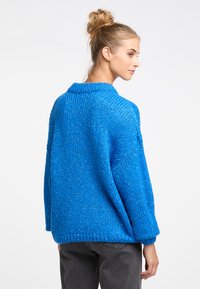 Oversized blue knitted sweater with a textured pattern, a wide collar, and cuffed sleeves. Features a loose fit and soft yarn.