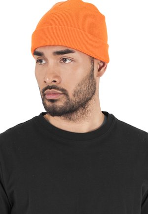 Orange ribbet strikket hue båret sammen med en sort crew neck t-shirt. Huen har en tætsiddende pasform med et foldet manchet-detalje.