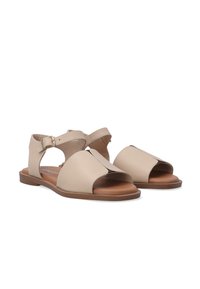 Beige leren gladiator sandalen met open teen, uitsnijdingen en enkelband met gesp. Bruine binnenzool en platte loopzool.