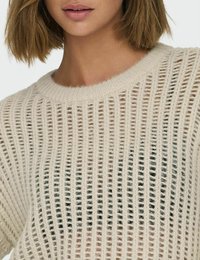 Hellbeige gestrickter Pullover mit geripptem Muster, weitem Rundhals-Ausschnitt und einem offenen Gewebe, das eine dunklere Schicht darunter enthüllt.