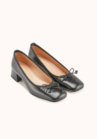 Chaussures à talon bloc en cuir noir avec un bout carré, ornées d'un petit nœud à l'avant et d'une finition lisse.