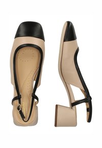 Beige leren schoenen met een zwarte gekapte neus. Voorzien van een kleine blokhak, uitsnijdingen en dunne zwarte bandjes. Zacht interieur met perforaties.