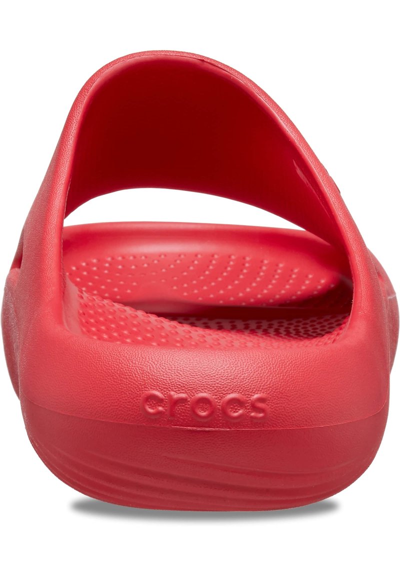 Rote Crocs mit einer glatten Kunststoffoberfläche, ausgestattet mit einem Riemen im Rücken und einem strukturierten Fußbett mit erhabenen Punkten für besseren Halt. Logo auf der Seite geprägt.