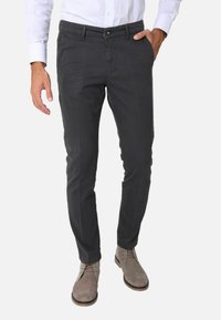 Chino in cotone grigio con vestibilità slim, caratterizzati da chiusura a bottone, tasche laterali e una consistenza morbida, abbinati a scarpe in suede grigio chiaro.