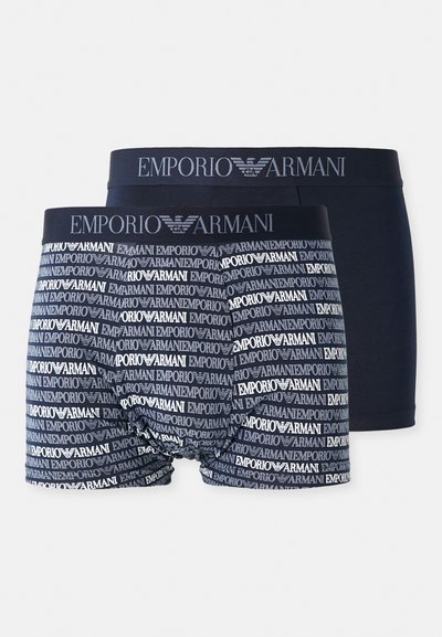 Dve pare moških bokseric: eno enobarvno mornarsko modro in drugo z vzorcem ponavljajočih se logotipov "Emporio Armani" v odtenkih modre in bele.