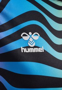 Sort stof med bølgede blå mønstre; præsenterer et hvidt logo med ordet "hummel." Struktureret overflade, sportydesign.