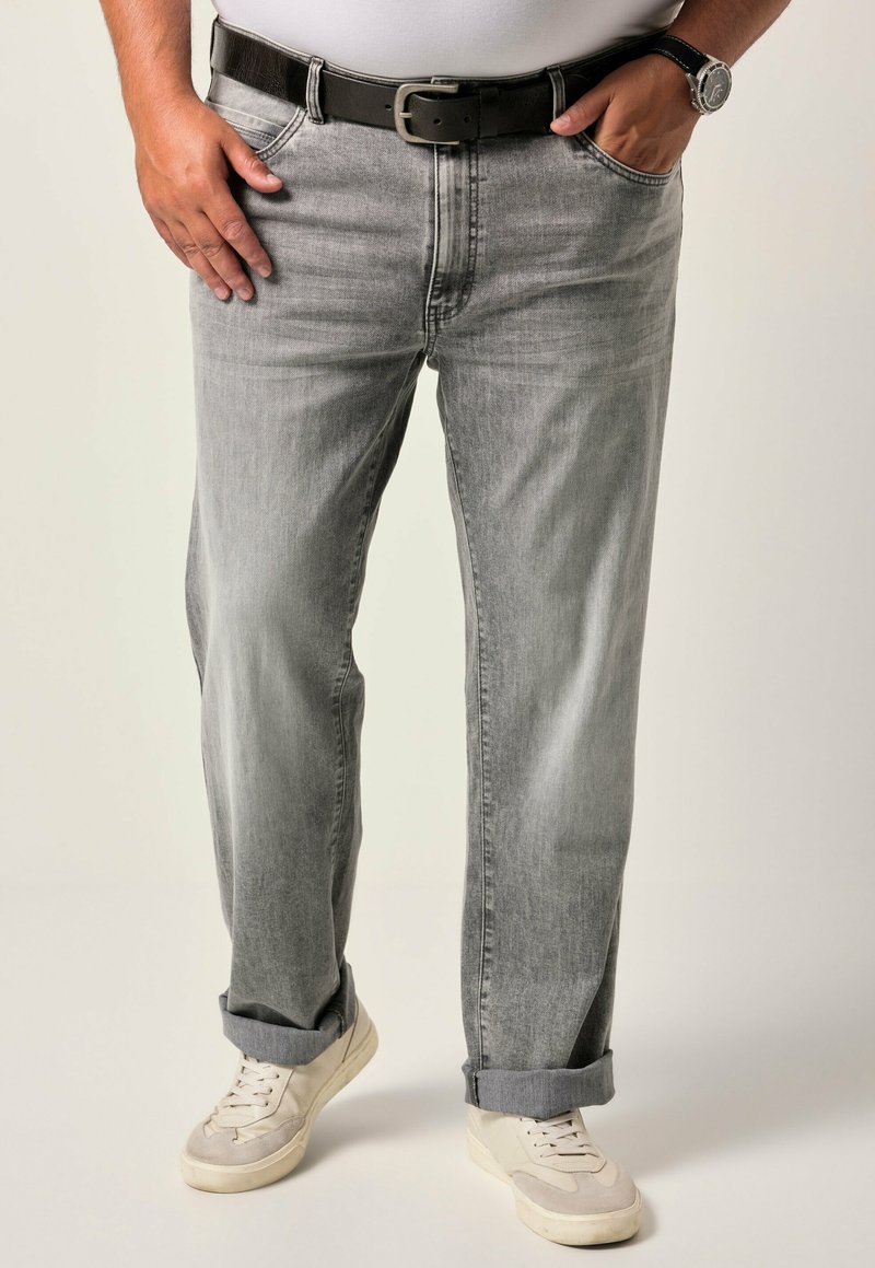 Jeans in denim grigio chiaro con sbiaditure visibili, vestibilità dritta, risvolti alle caviglie, abbinati a sneakers bianche e una cintura nera.