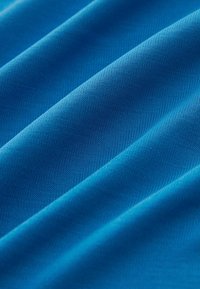 Niebieska tkanina o gładkiej powierzchni, z delikatnym połyskiem i widoczną teksturą. Zauważ diagonalny wzór splotu i miękki układ.