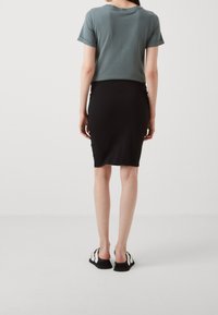 Kortärmad, åtsittande topp i teal som är matchad med en svart, knälång pennkjol, kompletterad med svarta halkskor med vita accenter.