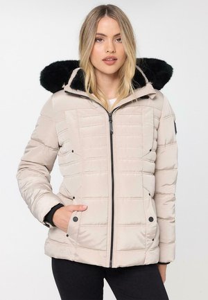 Veste rembourrée beige clair avec fermeture éclair sur le devant, capuche en fausse fourrure noire et texture matelassée. Comprend des poches latérales et des poignets côtelés.
