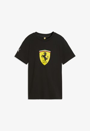 Sort t-shirt med korte ærmer og gul Ferrari-skjoldlogo med en sort opstigen hest og røde, hvide og grønne striber over emblemet.