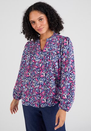 Blusa a maniche lunghe con stampa floreale nei colori rosa, blu e crema. Presenta un collo a V e dettagli arricciati sulle spalle. Tessuto leggero.