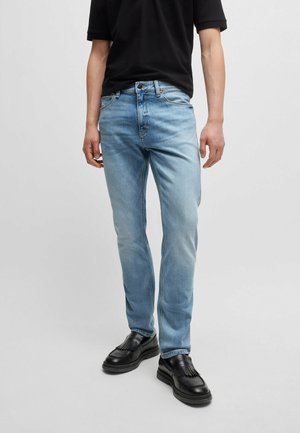 Lichtblauwe jeans in een slim fit, gemaakt van denim met een vervaagde wassing. Bevat vijf zakken, riemlussen en een ritsluiting. Draagt met zwarte schoenen.