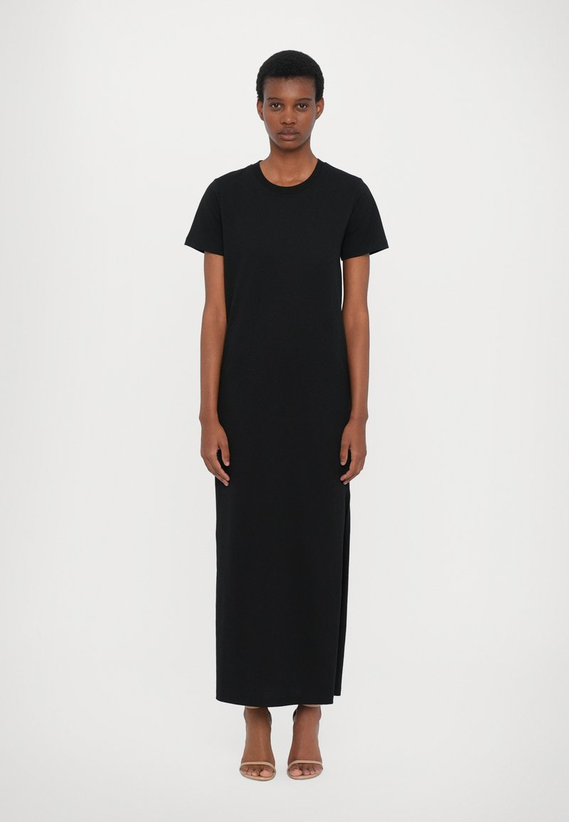 Rochie maxi neagră, cu mâneci scurte, realizată dintr-un material moale, cu un croi drept și fante laterale. Design simplu, fără modele sau accesorii vizibile.