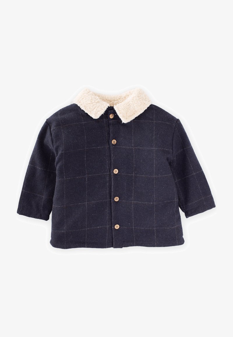 Modra jakna s gumbi in puhastim bež ovratnikom, ki ima vzorec mreže in tričetrtinske rokave, izdelana iz mehke tkanine.