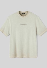 T-shirt beige à manches courtes en tissu doux, avec un col rond et un texte noir : « CONCENTREZ-VOUS SUR CE QUI COMPTE, OUBLIEZ LE RESTE. »