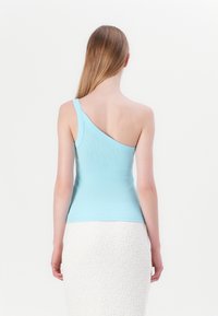En-skulder, lyseblå ribbet tanktop med en tætsiddende form, parret med en struktureret hvid nederdel. Glat stof, minimale designdetaljer.