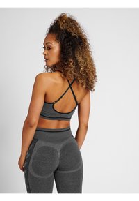 Grå sportbh med ett korsande remdesign och matchande högmidjade leggings med strukturerade detaljer och en åtsittande silhuett.