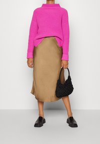 Pull côtelé fuchsia, jupe en satin beige, sac à main noir texturé, et chaussures noires sans lacets. Accent sur les couleurs vives et les textures variées.