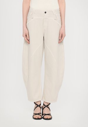 Beige wide-leg trousers with a high waist, featuring side pockets and curved stitching details. Made from a smooth cotton blend fabric.