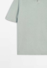 Polo tricoté gris clair à manches courtes avec col, poignets et ourlet côtelés sur fond blanc.