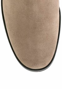Chaussure en daim beige avec une texture lisse et douce. Bout arrondi et bord de semelle noir. Design simple, sans motifs ni accessoires visibles.