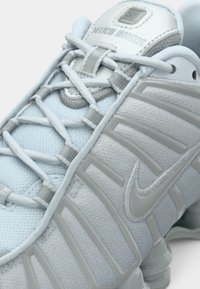 Απαλά μπλε αθλητικά παπούτσια Nike Shox με υφασμάτινη άνω επιφάνεια με υφή, μορφοποιημένα επικάλυψη και αντανακλαστικό ασημένιο λογότυπο στην γλώσσα.
