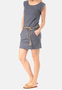 Námořnické šaty se zigzagovým vzorem, krátkými rukávy a opaskem v pase. Obsahují kapsy a mají volný střih. Nošeny s plochými sandály.