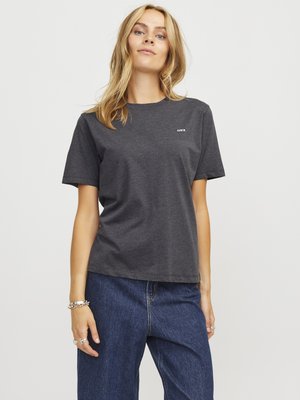 Grijze katoenen t-shirt met een ronde halslijn en korte mouwen, met subtiele branding op de linker borst. Gekleed met brede blauwe denim jeans.